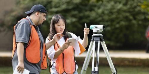 Two students survey a plot of land during a civil engineering class